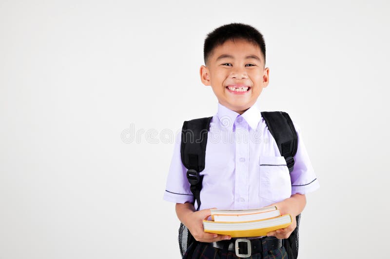 Portrait smile Asian little boy primary posing holding stack of books studio stock photo