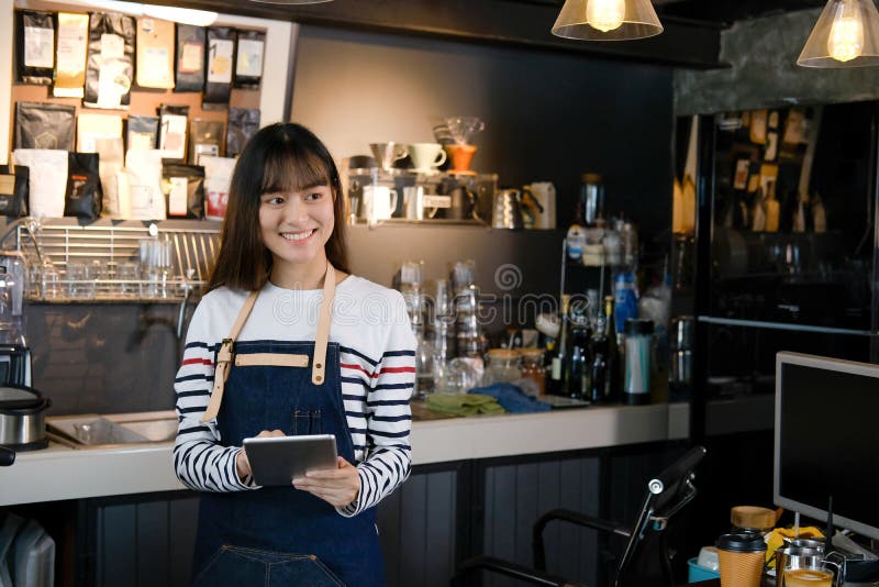 Portrait of smiling asian barista holding digital tablet at counter in coffee shop. Cafe restaurant service, food and drink indus royalty free stock image Portrait of smiling asian barista holding digital tablet at counter in coffee shop. Cafe restaurant service, food and drink indus royalty free stock image