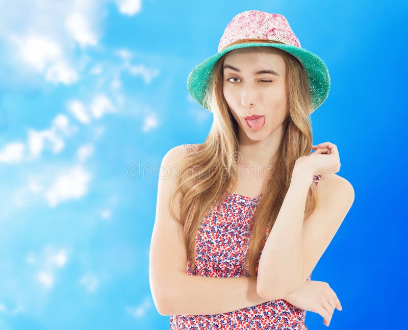 Portrait of a smiling attractive woman in summer dress and hat posing while standing and looking at camera isolated over blue royalty free stock photography Portrait of a smiling attractive woman in summer dress and hat posing while standing and looking at camera isolated over blue royalty free stock photography