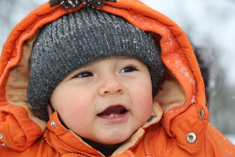 Portrait of Smiling Baby with Snow in Winter Clothes Stock Photo