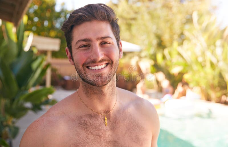 Portrait Of Smiling Bare Chested Man Outdoors With Friends At Summer Pool Party