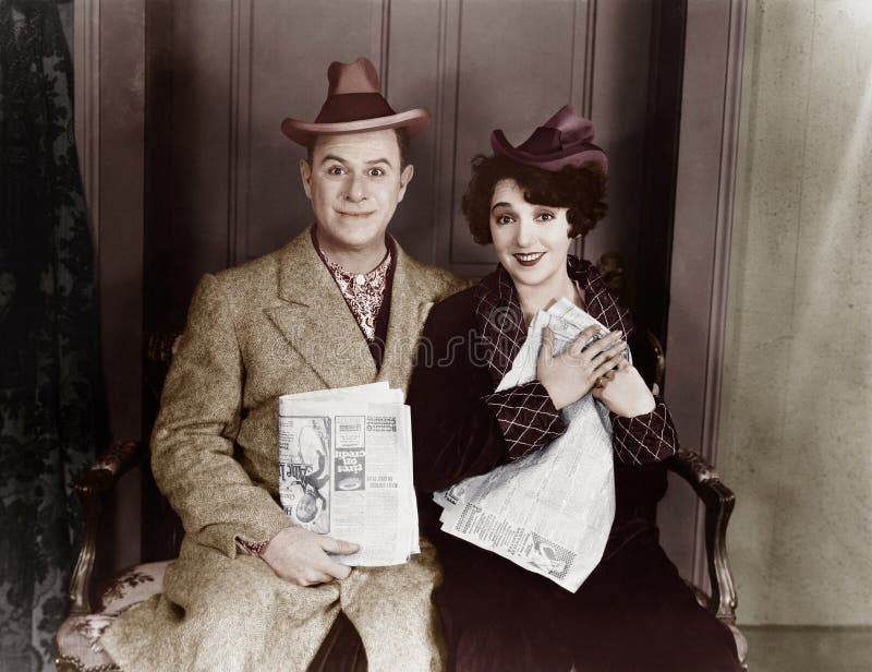 Portrait of smiling couple with newspapers (All persons depicted are no longer living and no estate exists. Supplier grants that there will be no model release issues.)