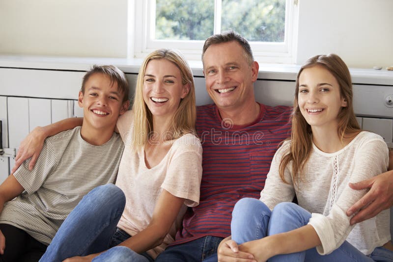 Portrait Of Smiling Family Relaxing On Seat At Home stock photos Portrait Of Smiling Family Relaxing On Seat At Home stock photos
