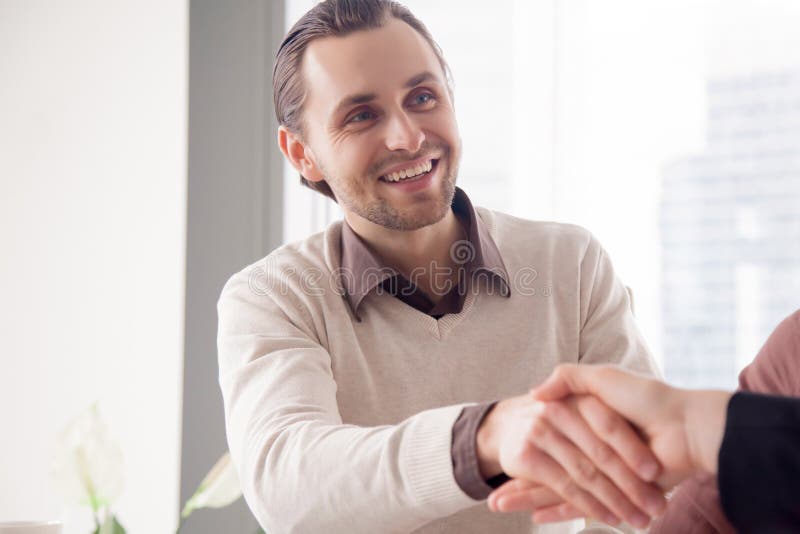 Portrait of smiling handsome businessman shaking female hand on