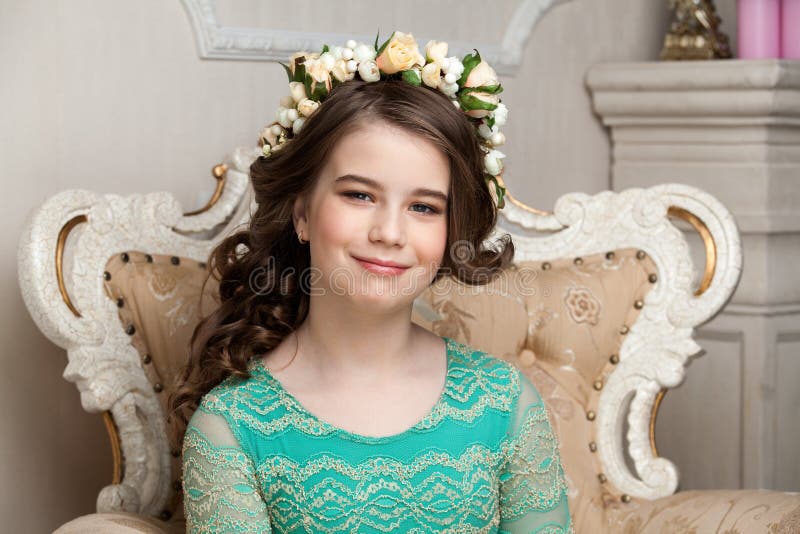 Portrait of a smiling little girl in the flower wreath sitting o