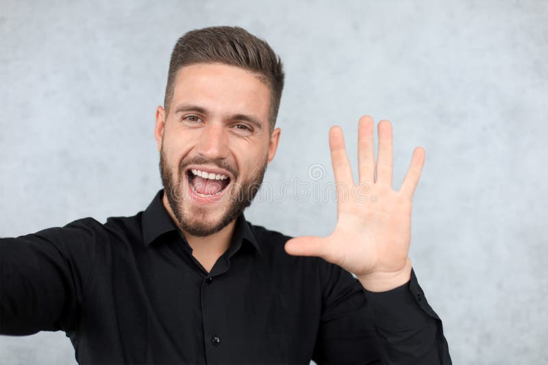 Portrait of smiling man with hand raised in greeting. High five concept stock photo Portrait of smiling man with hand raised in greeting. High five concept stock photo