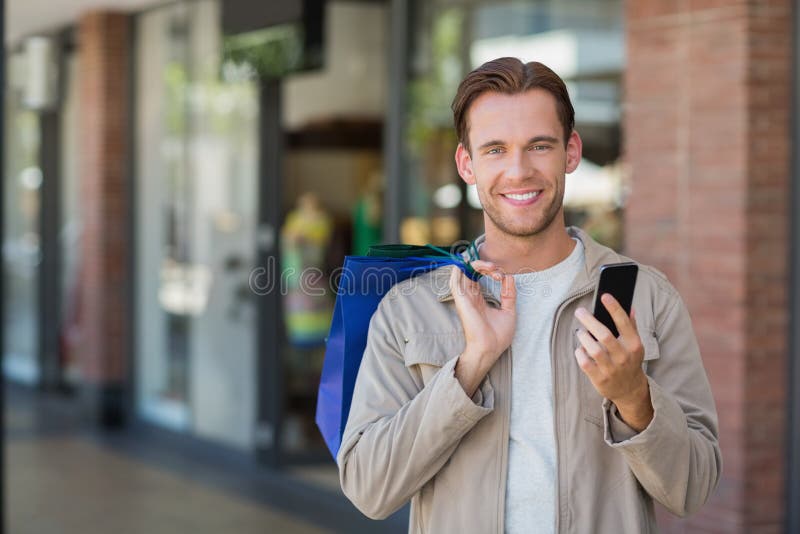 Portrait of a smiling man using his phone at the mall