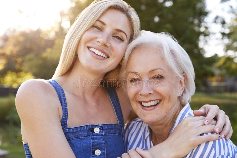 Portrait Of Smiling Mother Hugging Adult Daughter Outdoors In Summer Park