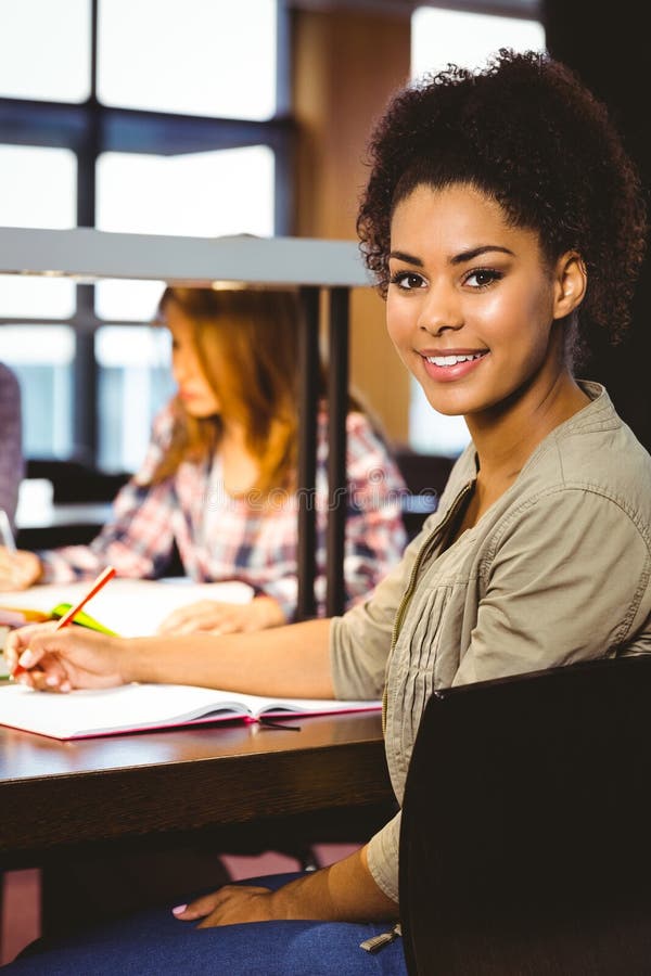 Portrait Of A Smiling Student Sitting At Desk Looking At Camera Stock