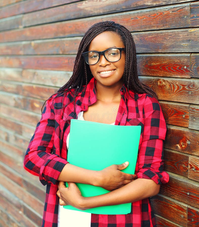 Portrait smiling young african woman in glasses holding folder over background