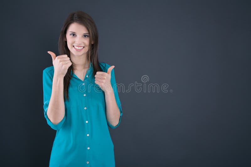 Portrait of a smiling young woman with thumbs up in school.