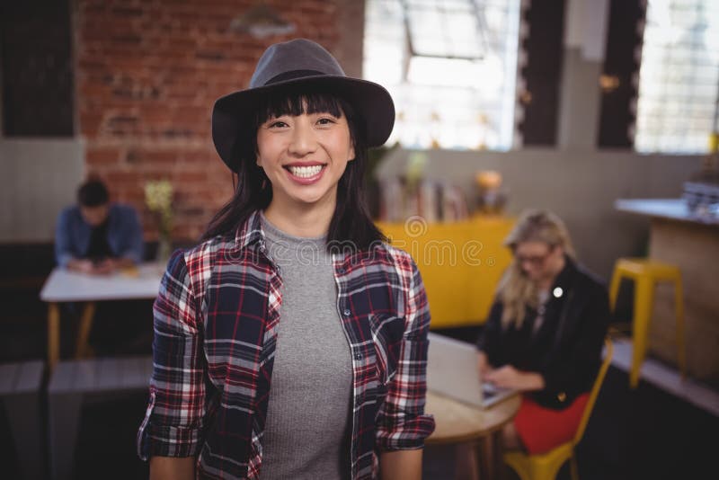 Smiling young woman wearing hat standing at coffee shop stock image Smiling young woman wearing hat standing at coffee shop stock image