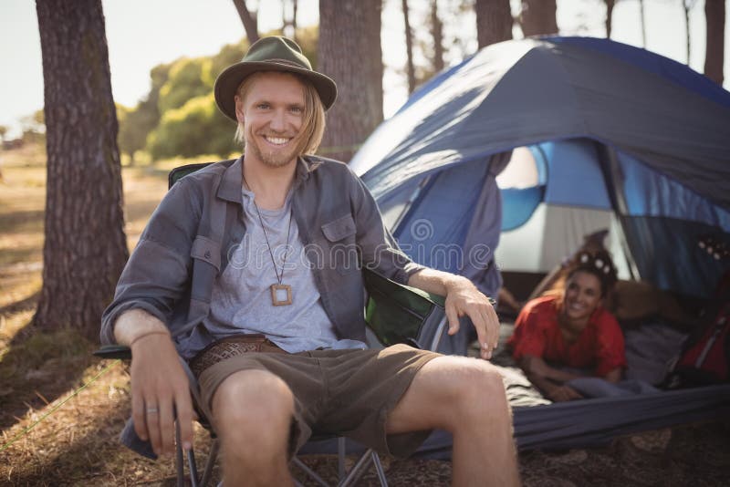 Portrait of smling man sitting on chair by tent stock photos Portrait of smling man sitting on chair by tent stock photos