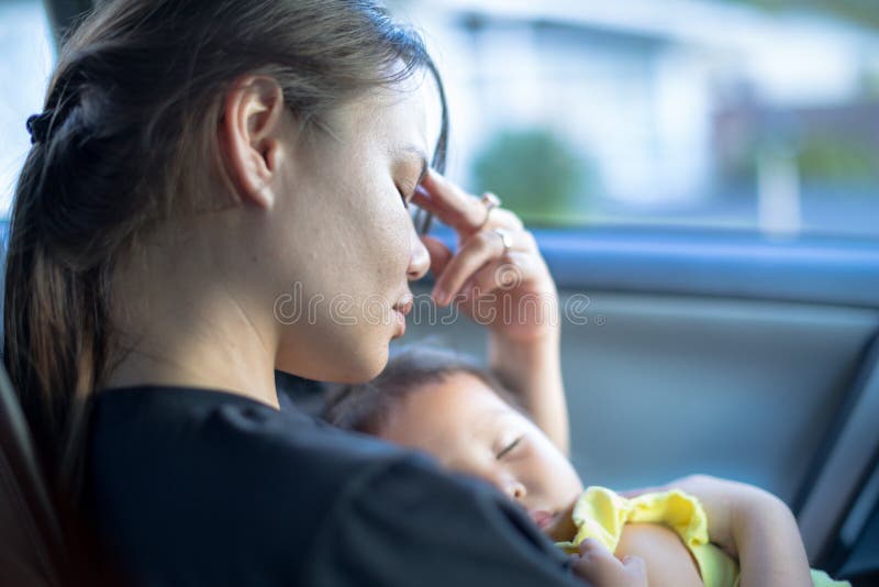 Portrait of a stressed mother trying to cope while she carries her sleeping baby in her arms