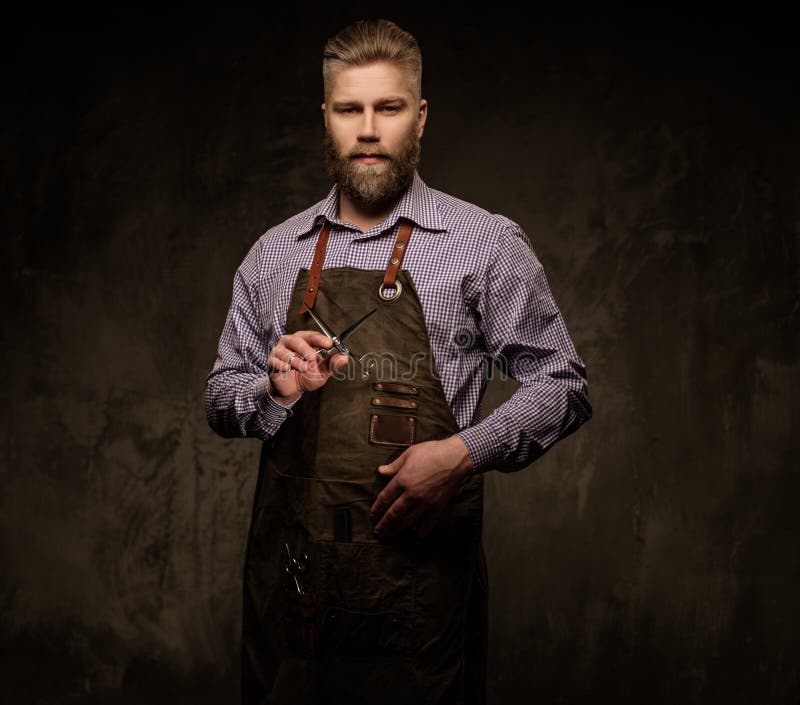 Portrait of stylish barber with beard and professional tools on a dark background.