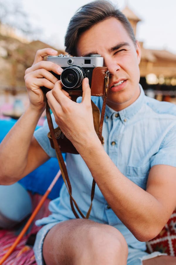 Portrait of stylish photographer in trendy light-blue denim shirt taking photo on blur background. Handsome young man royalty free stock images Portrait of stylish photographer in trendy light-blue denim shirt taking photo on blur background. Handsome young man royalty free stock images
