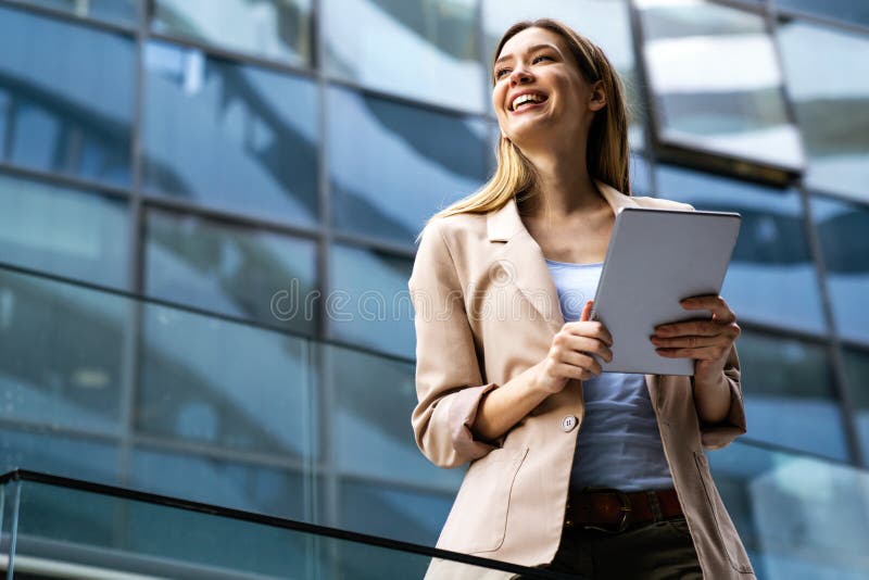 Portrait of a successful young business woman using digital tablet in front of modern business building. Portrait of a successful young business woman using digital tablet in front of modern business building