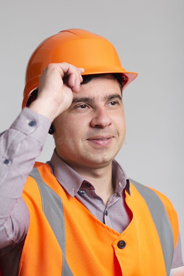 Portrait of Successful Young Construction Worker in Hard Hat on Grey Studio Background Greeting