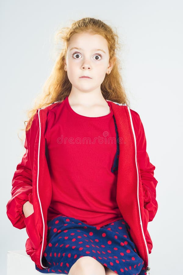 Portrait of Surprised Redhaired Caucasian Little Girl In Red Jacket and Polka dotted Skirt