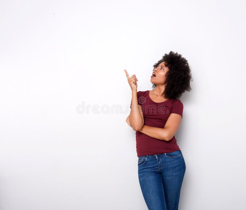 Portrait of surprised young african lady looking up and pointing on white background