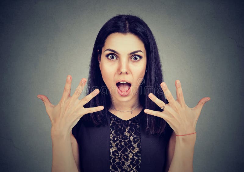 Portrait of a surprised young woman with wide open mouth and hands up in air