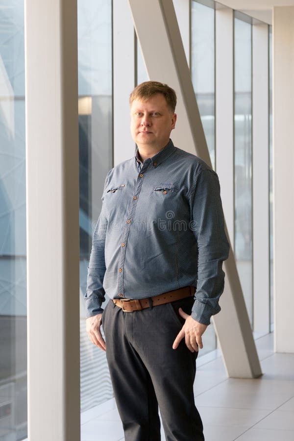 Portrait of a tall overweight man near large office windows.