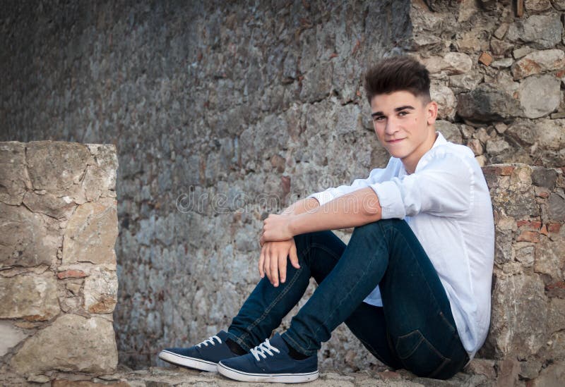 Portrait of a teenager. He is sitting in a stone wall. Dramatic stock images Portrait of a teenager. He is sitting in a stone wall. Dramatic stock images