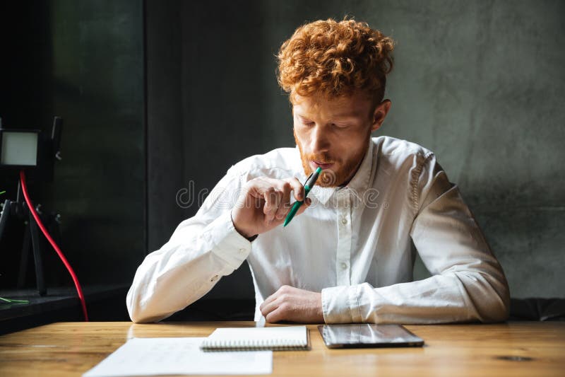 Portrait of thinking young readhead man in white shirt, sitting foto de archivo libre de regalías Portrait of thinking young readhead man in white shirt, sitting foto de archivo libre de regalías