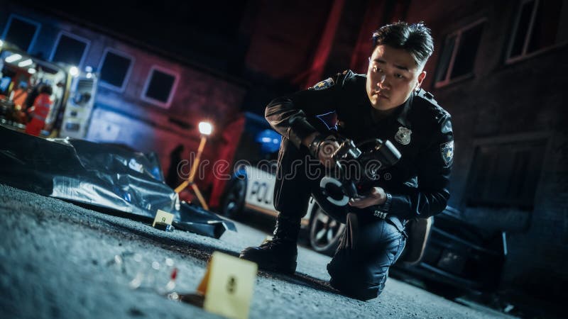 Portrait Tilted Shot of Male Asian Police Officer Taking Forensic Photos of Evidence Found Next to the Victim& x27;s Bagged Body on a Crime Scene. Policeman Archiving Hit and Run Car Accident Evidence.
