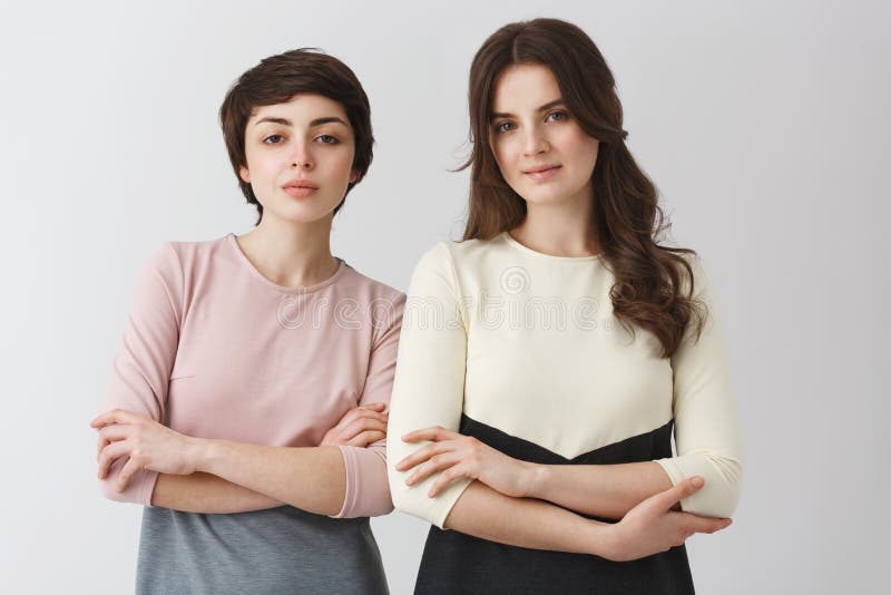 Portrait of two beautiful female university friends with dark hair, posing for graduation photo album in fashionable stock image Portrait of two beautiful female university friends with dark hair, posing for graduation photo album in fashionable stock image