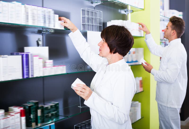 Portrait of two cheerful pharmacists working in modern farmacy