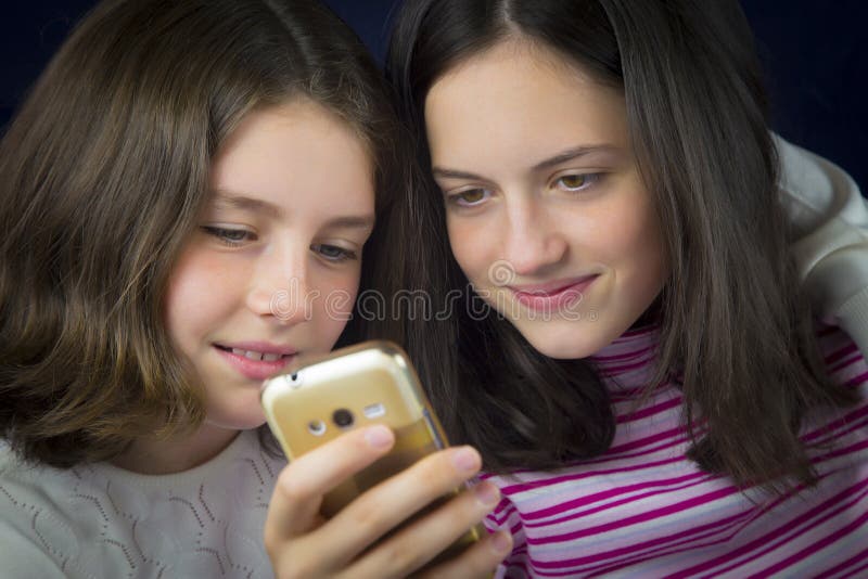 Portrait of two cute sisters looking at cell phone stock photos.