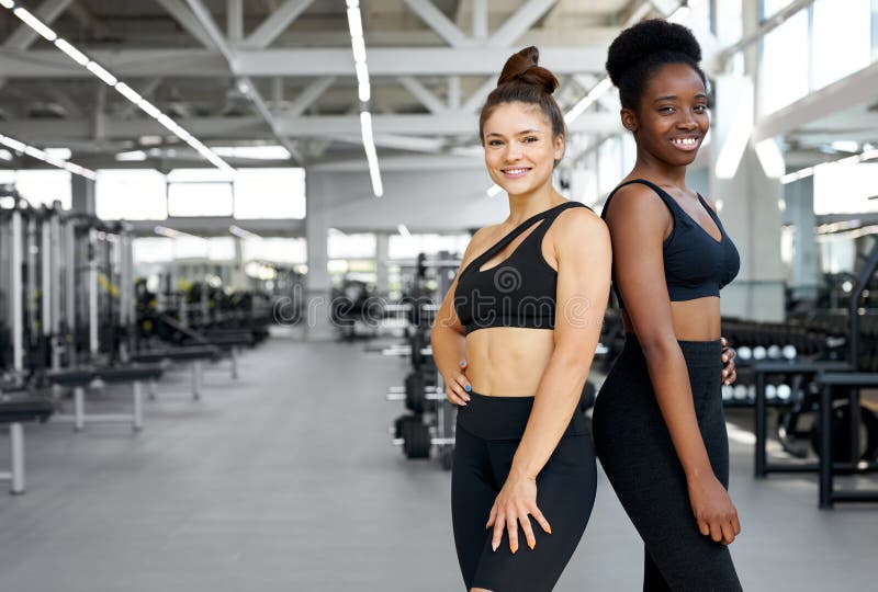 two fit girls training with personal trainer in gym, attractive