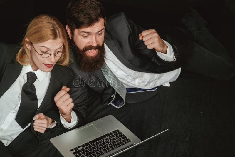 Portrait of two excited business people looking at a laptop screen. Hackers using laptops. Hackers hacking in the dark. stock photography