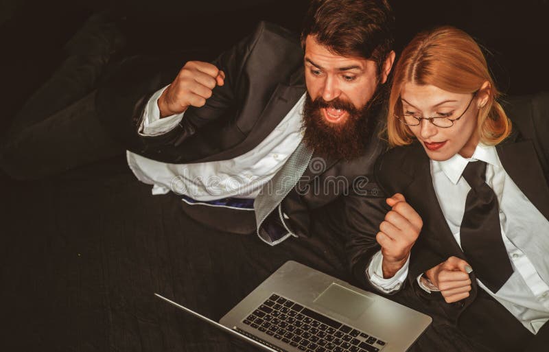Portrait of two excited business people looking at a laptop screen. Hackers using laptops. Hackers hacking in the dark. stock photography