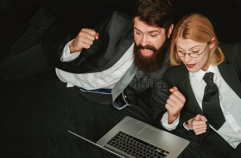 Portrait of two excited business people looking at a laptop screen. Hackers using laptops. Hackers hacking in the dark. royalty free stock photos