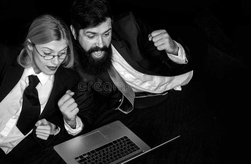 Portrait of two excited business people looking at a laptop screen. Hackers using laptops. Hackers hacking in the dark. stock images