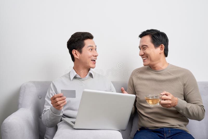 Portrait of a two excited young men holding laptop computer while pointing finger at a credit card and celebrating stock photos Portrait of a two excited young men holding laptop computer while pointing finger at a credit card and celebrating stock photos