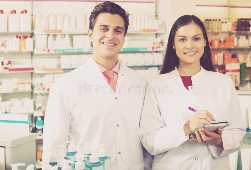 Portrait of two attracitve friendly pharmacists working in modern farmacy. Portrait of two attracitve friendly pharmacists working in modern farmacy