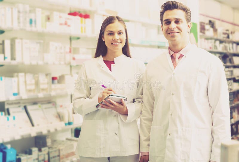 Two smiling friendly pharmacists working in luxury pharmacy. Two smiling friendly pharmacists working in luxury pharmacy