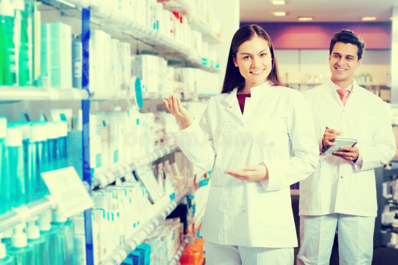 Portrait of two smiling friendly pharmacists working in luxury pharmacy. Portrait of two smiling friendly pharmacists working in luxury pharmacy