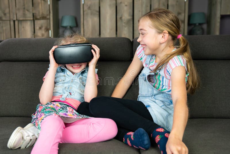 Portrait of two girls, they are having fun with a virtual reality headset at home royalty free stock image Portrait of two girls, they are having fun with a virtual reality headset at home royalty free stock image