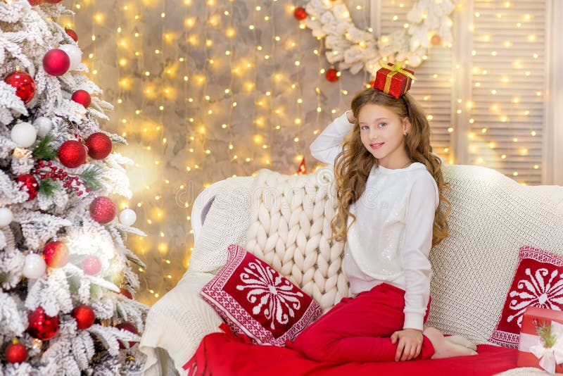 Portrait of two one young girls sisters close to white green Christmas tree. The girls in beautiful evening dresses clothes in New