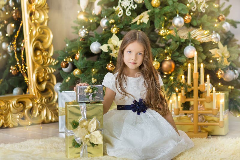 Portrait of two one young girls sisters close to white green Christmas tree. The girls in beautiful evening dresses clothes in New