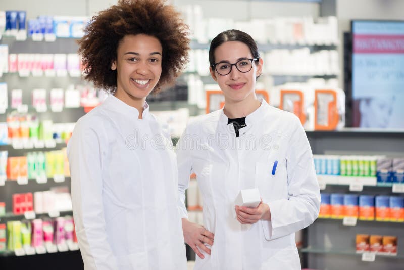 Portrait of two pharmacists smiling with confidence at work