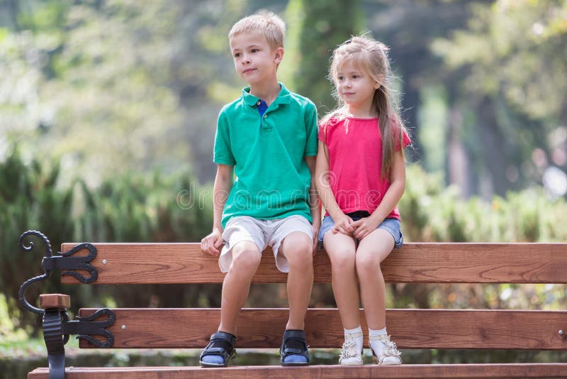Portrait of two pretty cute children boy and girl having fun time on a bench in summer park outdoors royalty free stock photo Portrait of two pretty cute children boy and girl having fun time on a bench in summer park outdoors royalty free stock photo