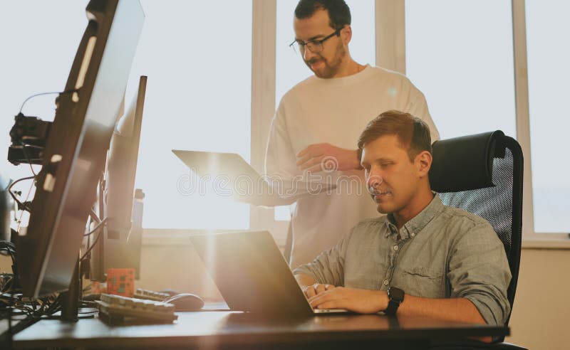 Portrait of two professional male programmers working on computer in diverse offices. Modern IT technologies stock photos