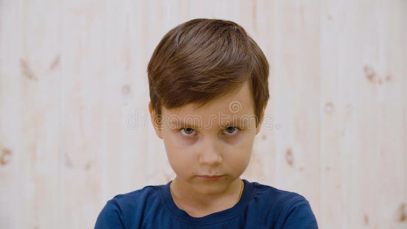 Portrait, un garçon sérieux qui regarde la caméra sur fond lumineux en studio Fermez le visage jeune garçon posant à la caméra Fa banque de vidéos
