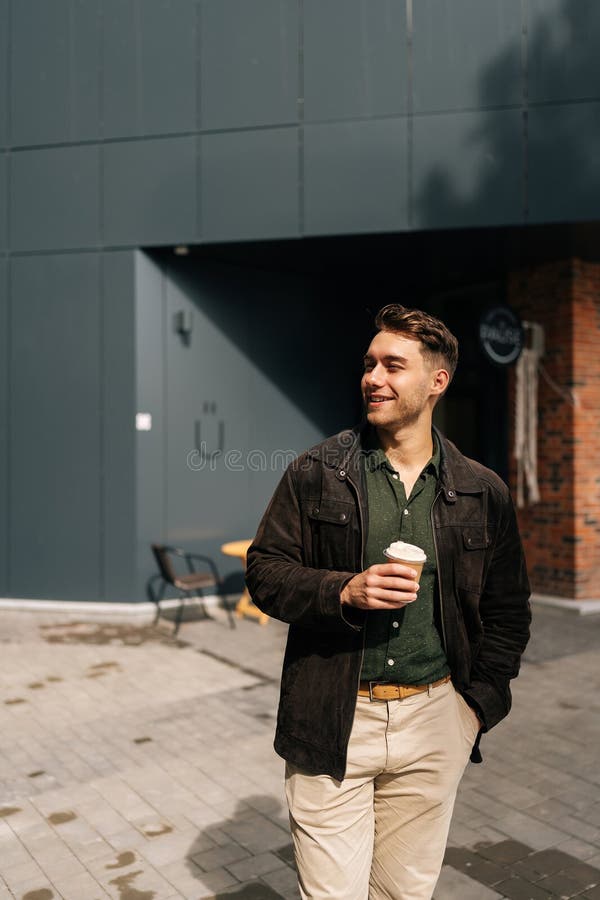 Portrait vertical d'un homme heureux tenant une tasse de café à emporter debout devant le café profitant du jour ensoleillé d'auto photo stock