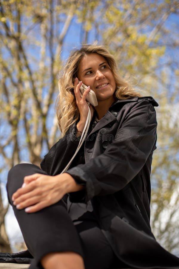 Portrait vertical d'une femme d'affaires blonde tannée parlant au téléphone le jour du printemps à l'extérieur. positif. images libres de droits